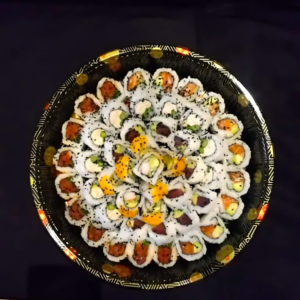 A large platter of Blue Koi Sushi rolls, featuring various fillings and toppings, on a dark background.