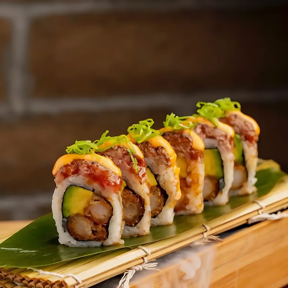 Blue Koi Sushi's shrimp tempura and avocado sushi rolls topped with seared tuna, sauce, and scallions.